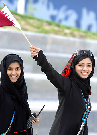 Volunteers waves outside athletes village of 2006 Asian Games in Doha, November 27, 2006.