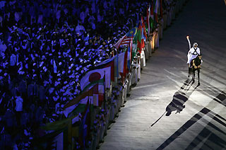 Sheikh Mohammad Bin Hamad Al-Thani, Qatar's equestrian team captain, holds the Asian Games torch as he rides a purebred Arab gelding past the flags of countries participating in the Games during the opening ceremony of the 15th Asian Games at Khalifa Stadium in Doha December 1, 2006. 