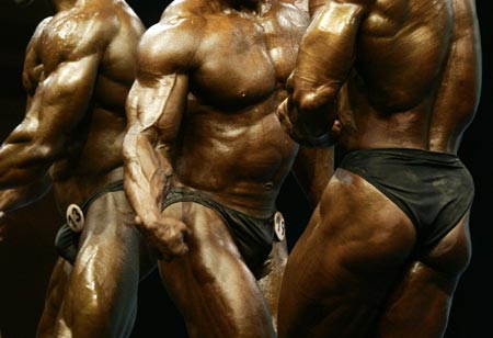 (L-R) Oman's Haji Shaban Eid Pashok Al Balushi, Hong Kong's Chan Yun-to and South Korea's Kim Myung-sub flex their muscles in the men's under-75kg bodybuilding event at the Asian Games in Doha December 8, 2006. Chan won the gold medal.