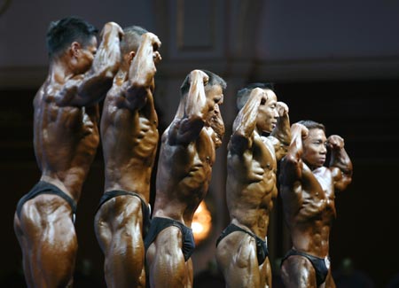 Competitors in the bodybuilding men's -60kg category elimination round line up and pose in front of the judges at the 15th Asian Games in Doha December 8, 2006. 