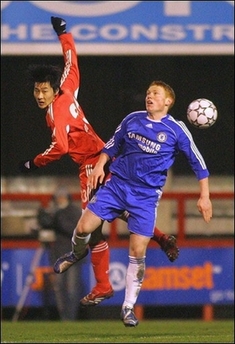 Michael Woods (R) of Chelsea and Lei Wei of Team China jump for the ball during a friendly match at Brentford's Griffin Park stadium in west London, 5 February.