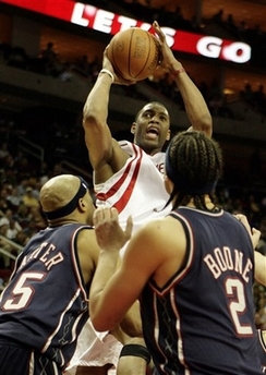 Houston Rockets forward Tracy McGrady drives to the basket to score against New Jersey Nets' Vince Carter, left, and Josh Boone (2) during the third quarter of an NBA basketball game, Friday, March 9, 2007, in Houston. The Rockets defeated the Nets, 112-91.(AP