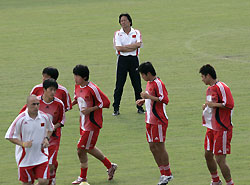 China's soccer team coach Zhu Guanghu (top) watches his players warm up during a training session for the 2007 AFC Asian Cup soccer tournament in Kuala Lumpur July 12, 2007. 