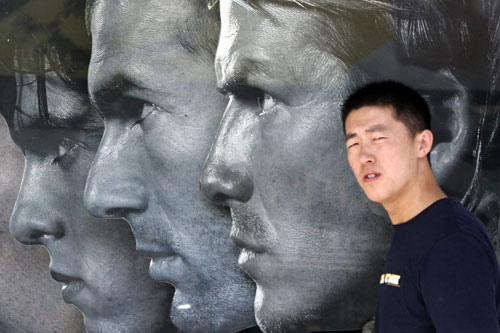 A shopper walks past an advertisement of World Cup soccer players in Beijing 