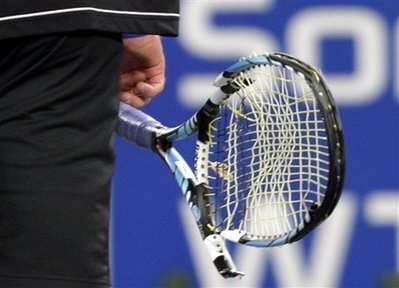 Andy Roddick, of the United States, carries his broken racquet off the court after smashing it against the ground during his quarterfinal match against Spain's Juan Carlos Ferrero, at the China Open tennis tournament in Beijing Friday Sept. 26, 2008. [Agencies] 