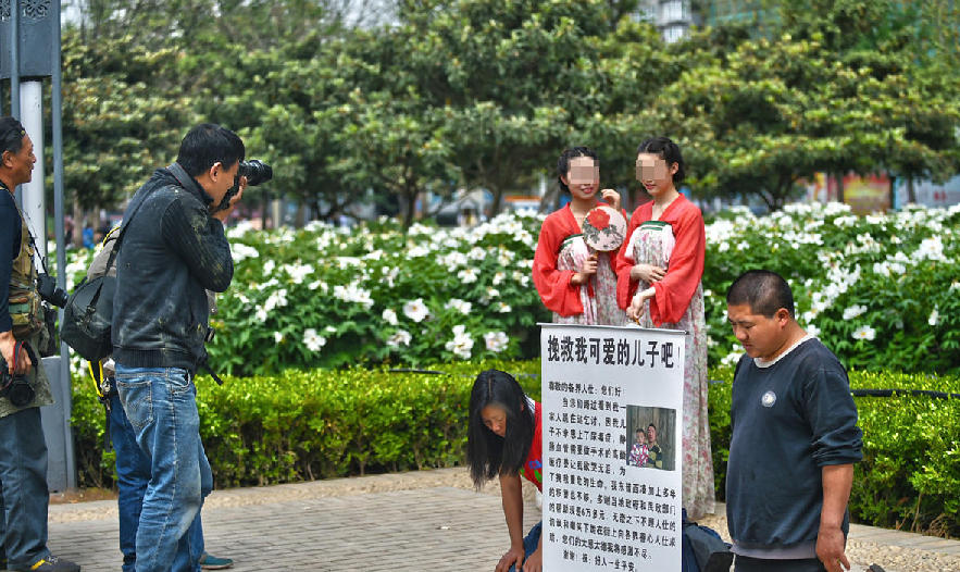 一边是夫妇跪地乞讨 一边是美女羞笑拍照