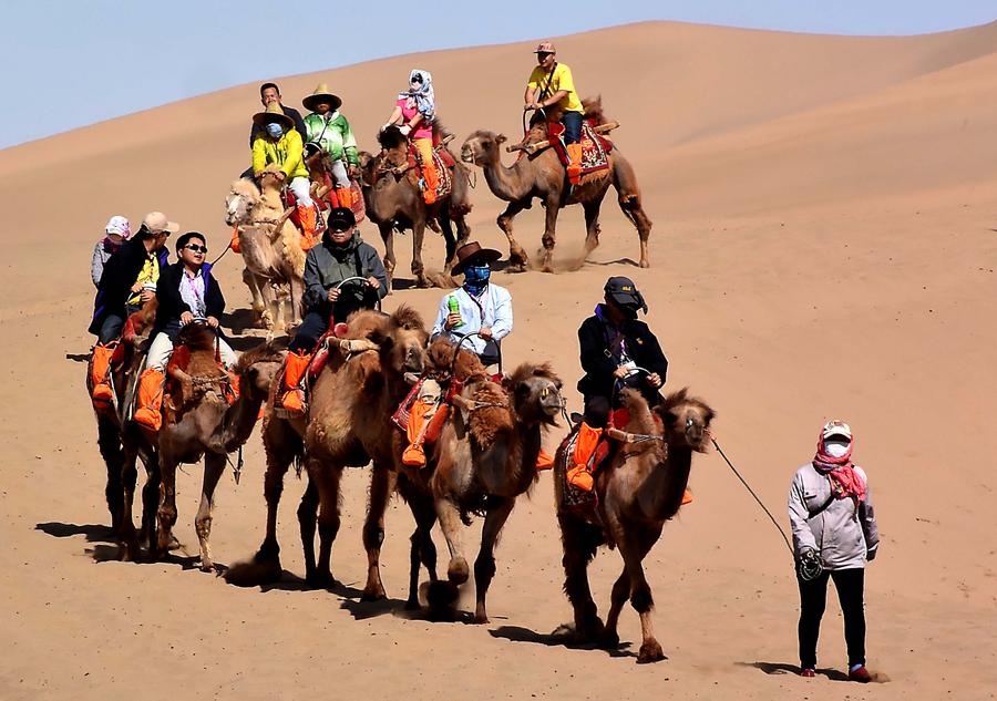 Tourists try camel riding at Mingsha Hill desert