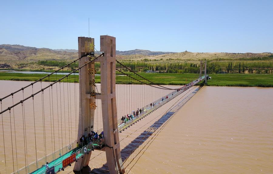 Tourists walk on glass bridge across Yellow River in Ningxia