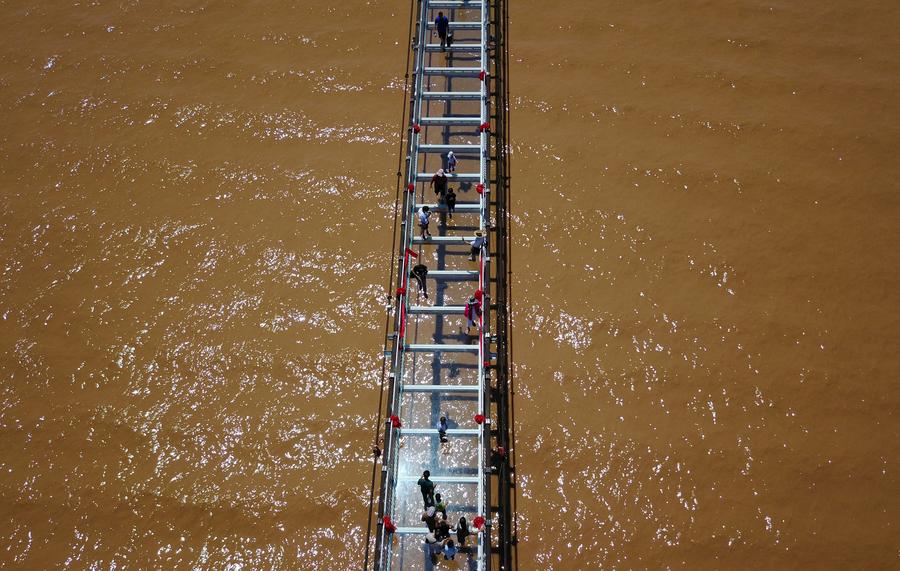 Tourists walk on glass bridge across Yellow River in Ningxia
