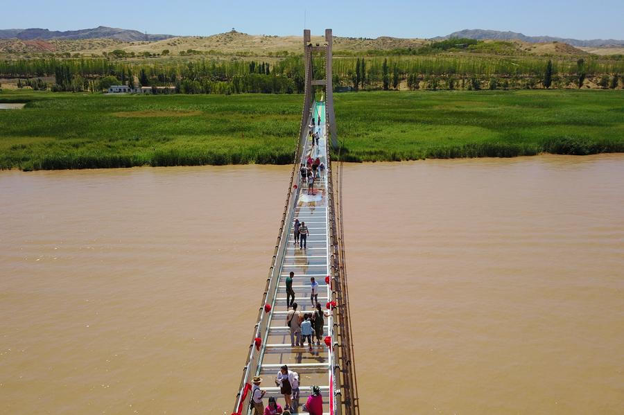 Tourists walk on glass bridge across Yellow River in Ningxia