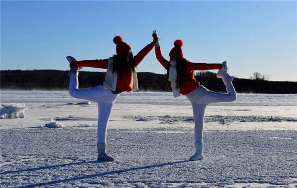 Yoga enthusiasts practice on frozen river in Heilongjiang