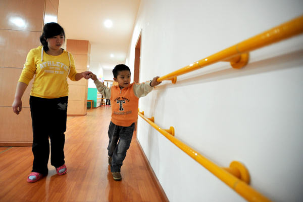 脑瘫儿童小靖在老师的帮助下练习行走
