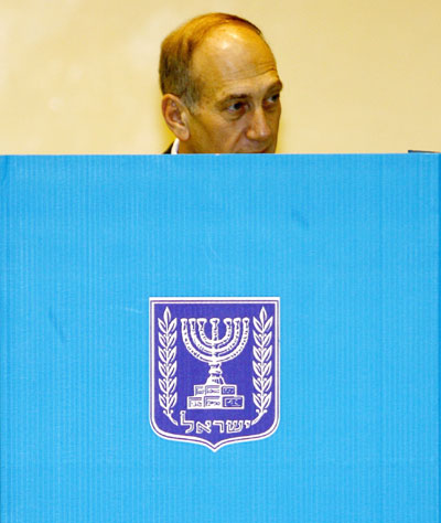 Israeli interim Prime Minister Ehud Olmert picks his ballot behind a voting booth in Jerusalem March 28, 2006. Israelis began voting in an election on Tuesday that interim Prime Minister Ehud Olmert has called a referendum on his plan to uproot remote settlements in the West Bank if peacemaking with the Palestinians stays frozen. 