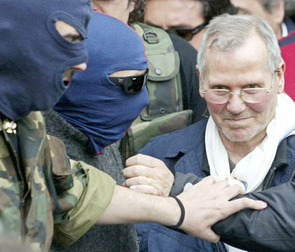 Italian police officers lead Sicilian Mafia boss Bernardo Provenzano (R) from a police station in the southern city of Palermo April 11, 2006. Provenzano, the undisputed chief of the Sicilian Mafia who had been on the run for more than four decades, was arrested while hiding in a farmhouse near Corleone in Sicily on Tuesday, officials said.