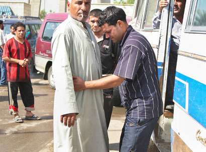 A passenger is frisked before boarding a public bus at the main terminal in central Baghdad April 13, 2006. Public buses have been the target of recent attacks by insurgents, with an explosion on a small bus killing three people in eastern Baghdad on Tuesday, police said.