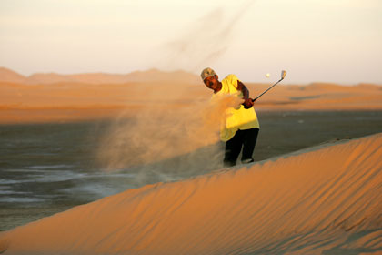Namibian Johnny Shebel plays a shot on a roadside desert golf track in Walvis Bay, Namibia in this May 16, 2006 file photo. The nine-hole course dubbed the "West Side Club" has no greens or tees, water or grass. Stinging sand and gusts of wind whistle through a lone row of palm trees on the edge of the forbidding Namib desert. 