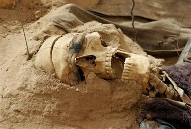 A human skull with blindfold still on lies on a mass grave containing human skeletons and clothes from persons allegedly executed during the regime of former President Saddam Hussein and now unearthed in a shallow grave, in a remote desert south of Baghdad in Iraq Saturday, June 3, 2006. U.S. forensic expert and project director Sonny Trimble said they have found 18 grave sites, with two of them already excavated so far. (AP Photo/