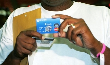 A survivor of Hurricane Katrina holds a debit card from FEMA outside the Reliant Center in Houston in this Sept. 9, 2005 file photo. The government doled out as much as $1.4 billion in bogus assistance to victims of Hurricanes Katrina and Rita, getting hoodwinked to pay for season football tickets. [AP]
