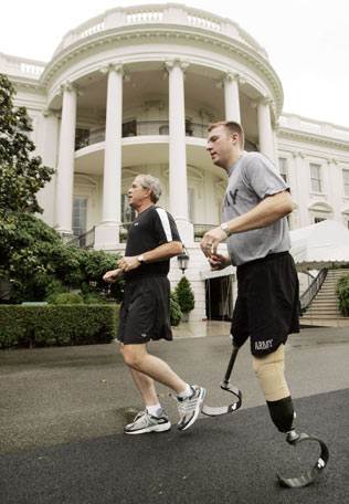U.S. President George W. Bush (L) jogs with Iraq war double-amputee U.S. Army soldier SSgt Christian Bagge, of Eugene, Oregon, along the jogging path on the South Lawn of the White House in Washington June 27, 2006. 