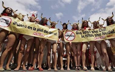 Animal rights activists hold up banners before a sprint, with runners wearing just underwear or even less, to protest the running of the bulls, in Pamplona, Spain, Wednesday, July 5, 2006. The run proceeded along part of the route that will see thrillseekers dash ahead of a pack of six fighting bulls and six meek steers starting Friday for eight days. Banner at left reads: Put yourself in the bull's skin!' (AP Photo