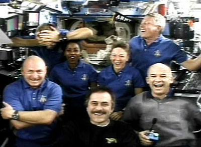 Piers Sellers (top, L) covers his head as his crewmates laugh after he was described as the spacewalker who lost the spatula during a crew news conference from aboard the International Space Station in this view from NASA TV July 14, 2006. The members of the crew are front row (L-R) Pilot Mark Kelly, ISS Commander Pavel Vinogradov, Jeff Williams, and back row, Sellers, Stephanie Wilson, Lisa Nowak and Mike Fossum. 