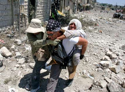 An elderly Lebanese woman is rescued by unidentified foreign journalists in the battered village of Bent Jbeil in southern Lebanon July 31, 2006. International pressure for a swift ceasefire in Lebanon mounted on Monday, France and Germany saying Israel's partial pause in air strikes was not enough and Russia calling for an immediate suspension of hostilities. [Reuters]