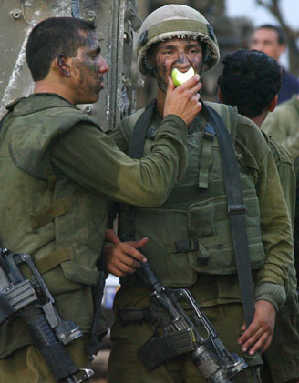 Israeli soldiers share an apple as they have a break along the Israel-Lebanon border after a mission in the Lebanese village of Kafar Kilathe, close to the Israeli village of Metula, early August 1, 2006. [Reuters]