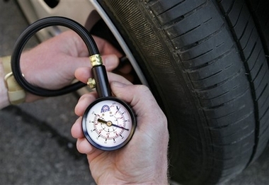A motorist uses a gauge to check air pressure in a tire Saturday, July 29, 2006, in Portland, Maine. Some motorists are inflating their tires with nitrogen instead of air because nitrogen-filled tires maintains pressure longer and may improve gas mileage. [AP]