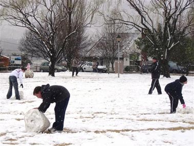 Residents frolic in the snow in Clarens, South Africa, Wednesday, Aug. 2, 2006. While Americans sweat through a heat wave, the country is facing some of the harshest winter weather in years. At least four people have been reported killed, police said. Heavy snow, rain and rockfalls closed mountain roads in parts of the interior, including a border post with Lesotho, according to local news reports. (AP Photo