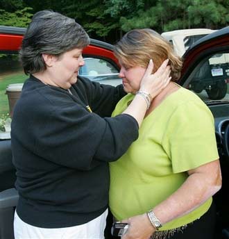 Pam Paugh, left, and Paulette Davis, sisters of Patsy Ramsey, hug in front of the family home in Roswell, Ga. Wednesday, Aug. 16, 2006 after hearing that a man was arrested in Thailand in connection with the 1996 slaying of their niece JonBenet Ramsey. Federal officials familiar with the case, who spoke on condition of anonymity, said the man was already being held in Bangkok on unrelated sex charges. The girl was found beaten and strangled in the basement of the family's home in Boulder, Colo., on Dec. 26, 1996.