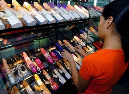 A shop employee arranges a display of sex toys