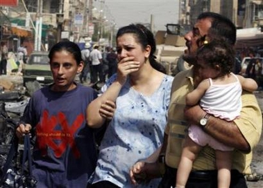 Residents walk away from the scene of a car bomb attack which targeted the convoy of Iraq's Industry Minister Fawzi al-Hariri in Baghdad, October 4, 2006. 