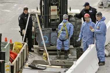 Port Authority police officers and workers at ground zero stand over a hole in the pavement on the West side of the site Monday, Oct. 23, 2006 in New York. Searchers who have yet to unearth more than half the underground sites apparently overlooked during the initial excavation of ground zero have uncovered more than 100 pieces of human remains believed to belong to Sept. 11 victims. (AP