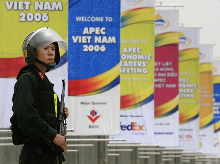 A police official keeps guard near banners waving from the gates of the National Convention Center, the site of the upcoming Asia-Pacific Economic Cooperation (APEC) meeting, in Hanoi November 12, 2006. 
