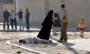 Salim Abdul Nabi lies on the ground grieving over death of son Ali, age 7, killed in an explosion in Baghdad, Iraq, Sunday, Nov. 12, 2006. A pair of roadside bombings targeting police patrols in Baghdad killed at least six passers-by and wounded six others, said police. (AP 