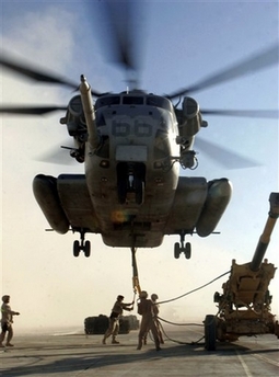 In this photo released by the U.S. Marine Corps, U.S. Marines with Combat Logistics Battalion Helicopter Support Team hook a M198 Medium Howitzer to an approaching CH-53 E helicopter, in Al Asad, Iraq, Wednesday, Nov. 29, 2006. The Marines plan on using the extra firepower to provide fire support in the province, where the southern California-based Regimental Combat Team 7 began combat operations. (AP
