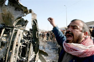 An Iraqi man cries out standing next to a destroyed car at the site of a bomb explosion in Kufa, 160 kilometers (100 miles) south of Baghdad, Iraq, Saturday, Dec. 30, 2006. A bomb planted on a minibus killed 17 people in a fish market in Kufa, while police imposed curfews in some Sunni areas to prevent any outbreak of violence after Saddam Hussein's execution. (AP