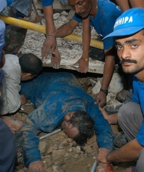 Pakistani firefighters and volunteers try to remove the dead body of firefighter from collapsed debris at a garment factory after a blaze in Karachi, Pakistan, Monday, Jan 15, 2007.