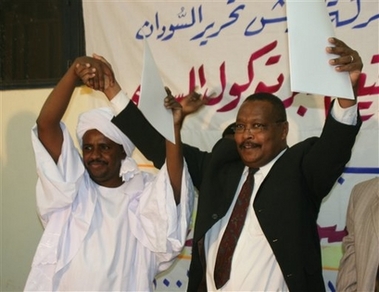 Darfur rebellion delegates from the Sudan Liberation Movement (right: Abu Obeida al-Khalifa) and the SLM 'Free Will' faction (left: Ali Majouhk) clasp hands after they signed a unity deal at the SLM's headquarters in Omdurman, Sudan on Sunday Jan 21 2007. 