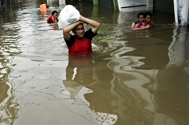 Indonesian man wade through their flooded neighborhood Sunday Feb. 4, 2007 in Jakarta, Indonesia. At least 20 people have been killed and 200,000 forced from their homes by floods in Indonesia's capital, an official said Sunday, as rivers overflowing from four days of rain inundated the city. (AP