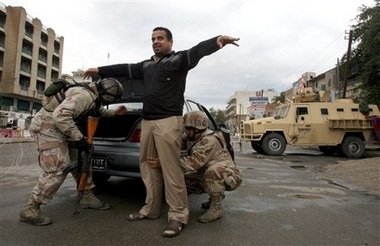 Iraqi army soldiers search a driver at a vehicle checkpoint in central Baghdad, Iraq, Friday, Feb. 16, 2007.