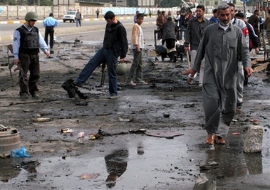 People pass by a scene of a car bomb attack in Baghdad, Iraq, Saturday, Feb. 24, 2007. 