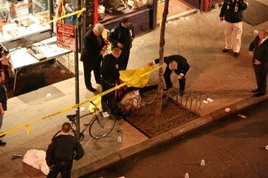 A policeman looks at the body of the unidentified gunman in the street in New York's Greenwich Village section Wednesday night March 14, 2007.