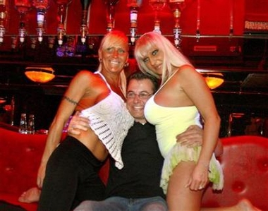 Banana Bar dancers Sunny (L) and Love (R) pose with a visitor during the open day of Amsterdam's red light district, March 31 2007.