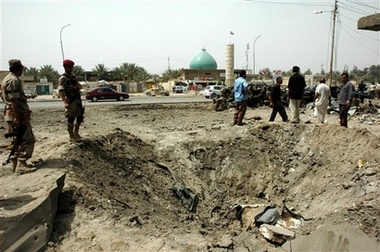 Iraqis stand around a crater after a pickup truck loaded with artillery shells exploded in the town of Mahmoudiyah, Iraq, 30 kilometers (20 miles) south of Baghdad, Sunday, April 8, 2007. At least 15 people were killed in the attack. (AP