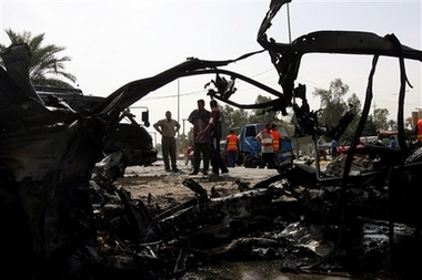 People stand by a twisted metal of what was a car bomb near university in Baghdad, Tuesday, April 10, 2007.