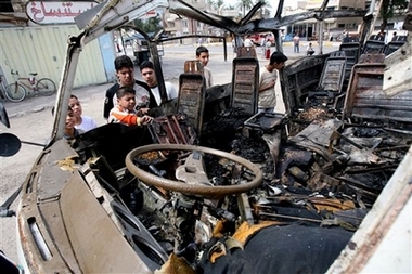 Iraqi kids look at a destroyed mini bus destroyed after a suicide bomber blew himself up in northwest Baghdad, Iraq, Sunday, April 15, 2007.