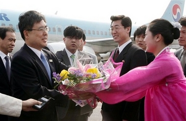 Chin Dong-soo, left, who leads the South's government delegation to North Korea, receives a bouquet of flowers from a North Korean woman upon his arrival at Pyongyang airport in Pyongyang, North Korea, Wednesday, April 18, 2007.