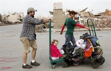 Kevin Hillhouse, left, and his wife, Melissa, push a hand truck with their daughter Alexis, 5, and their belongings as they make their way down Main Street in downtown Greensburg, Kan., Saturday, May 5, 2007, after a tornado struck Friday. The family was evacuating to shelters. The Hillhouse's moved here a week ago from Berryville, Ark. (AP