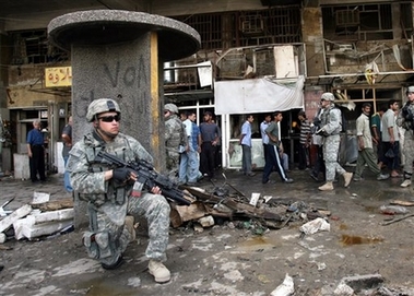 Iraqis and U.S. soldiers survey the scene following a car bomb attack in Baghdad, Iraq, Sunday, May 13, 2007. A parked car bomb exploded near a market in central Baghdad, killing at least 12 Iraqis, wounding 43 and damaging shops, police said. (AP 